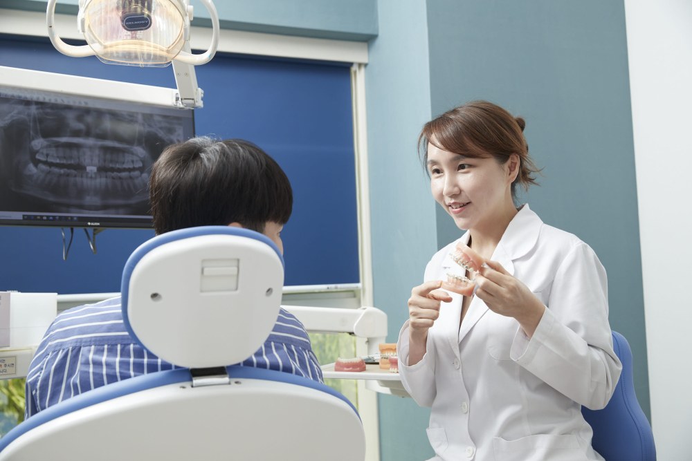 치과교정과 전문의 김선 원장이 치아 모형을 들고 환자에게 교정 치료를 설명하는 모습