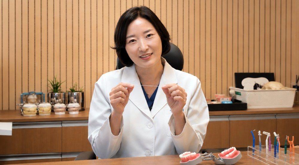 뉴욕치과 권수정 원장이 치실을 들고 치간 관리의 중요성을 설명하고 있다